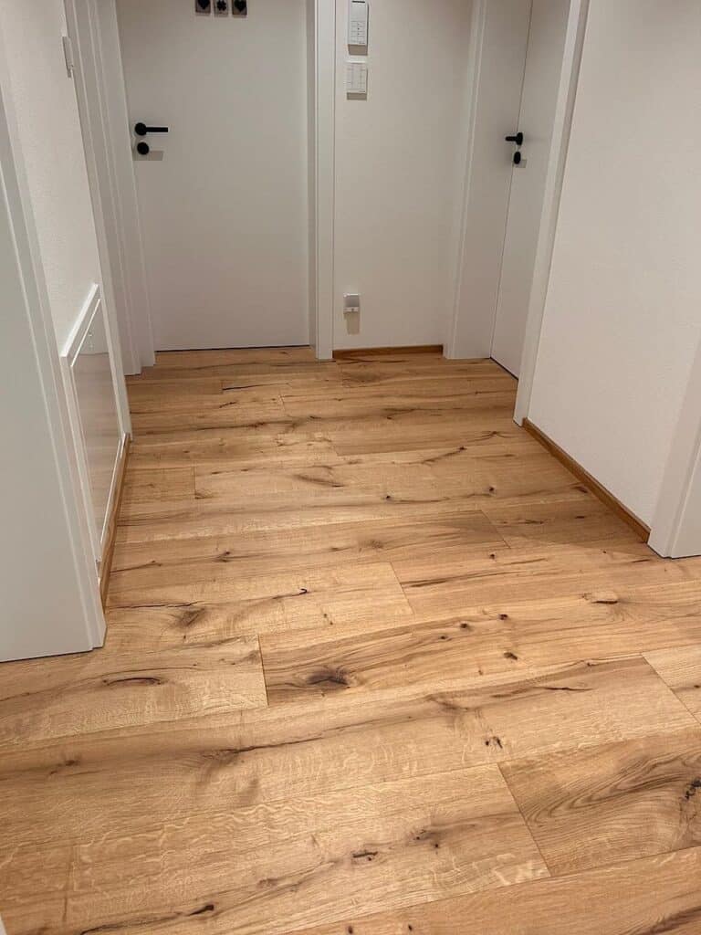 Ein heller Dielenboden in einem Flur mit weißen Türen.
