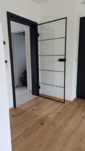 Eine Glastür für den Innenbereich mit einem schmalen schwarzen Rahmen und horizontalen Metallstreben.