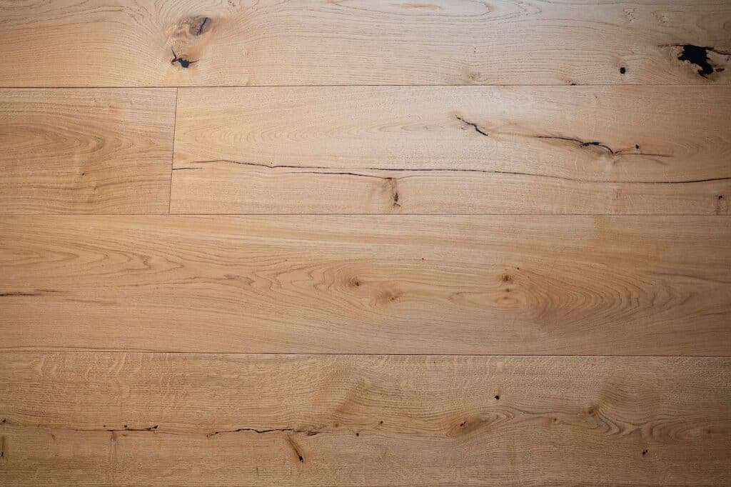 Helle Holzdielen mit sichtbarer Maserung, Astlöchern und kleinen Rissen.