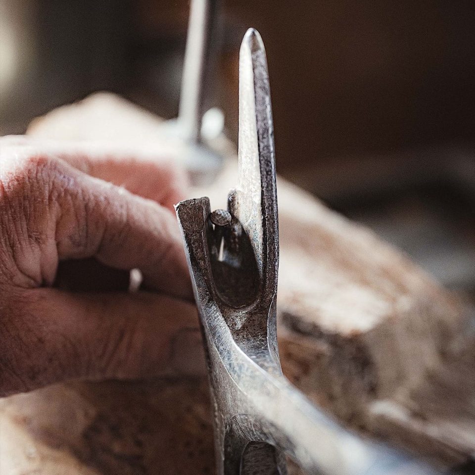 Eine Nahaufnahme einer Hand, die Holz hält, während in der Nähe ein Klauenhammer und eine Bohrmaschine positioniert sind, was auf eine laufende Schreinerarbeit hindeutet.