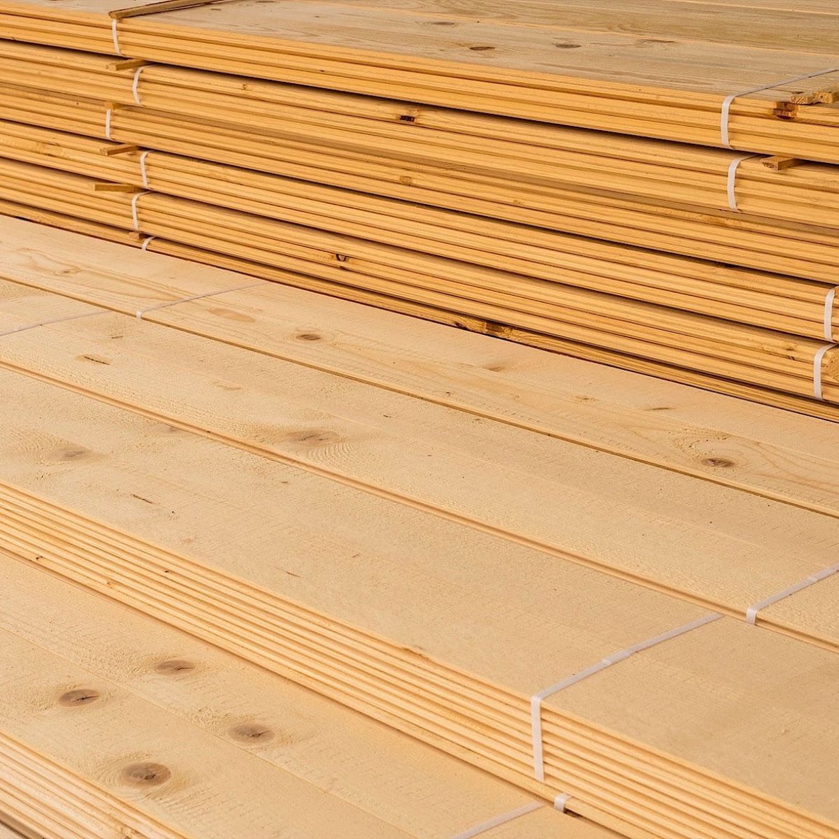 Eine Nahaufnahme von gestapelten Holzbrettern mit sichtbaren Maserungen und glatten, unbearbeiteten Oberflächen.