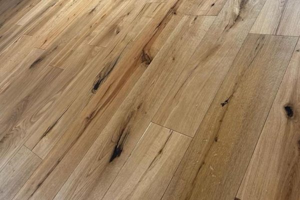 Hellbrauner Holzboden mit sichtbaren natürlichen Maserungen und Ästen, horizontal verlegt.