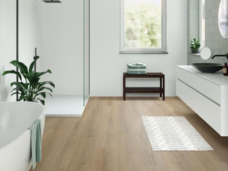 Modernes Badezimmer mit einer verglasten Duschkabine, einem weißen Waschtisch mit schwarzem Aufsatzwaschbecken und einem hellen Holzfußboden.
