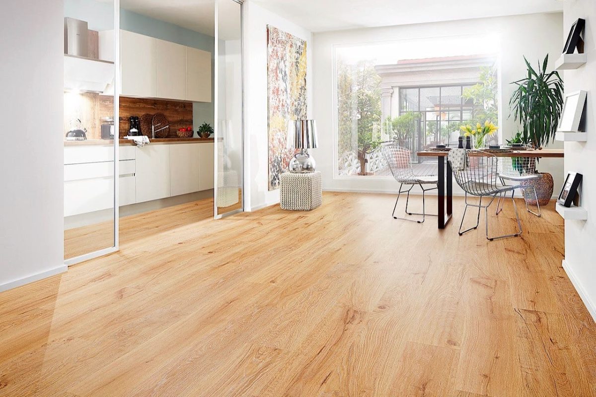 Moderner offener Wohnraum mit hellem Holzfußboden, Küche, Esstisch, großem Fenster, Zimmerpflanzen, Wandregalen und Glasschiebetüren.